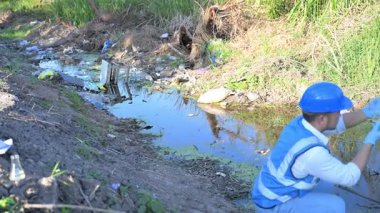 Kirli bir nehirde su kalitesini ölçen adam. 