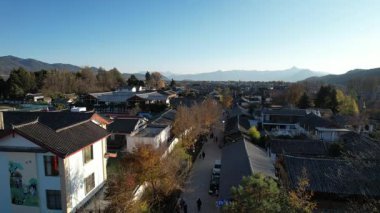 Baisha Kadim Kasabası 'nın üzerinde süzülen bir video. Çatıları vadi boyunca uzanan geleneksel evler. Dağlar ufku kucaklıyor 