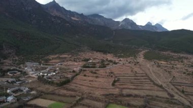 Baisha Antik Kasabası 'nın tepesinde vadi ve tarlalarla dolu bir video. Dağlar ufku kucaklıyor 
