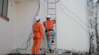 Tam Güvenlik İdaresi Mühendisleri Haberleşme Sinyalleri ve Endüstriyel Makineler İçin Bir Merdiven Tırmanmaya Hazırlanıyor