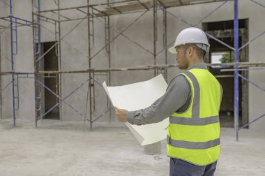 Büyük bir inşaat projesinin şantiyesinde çalışan Asyalı mühendis. İnşaat alanında fazla mesai.