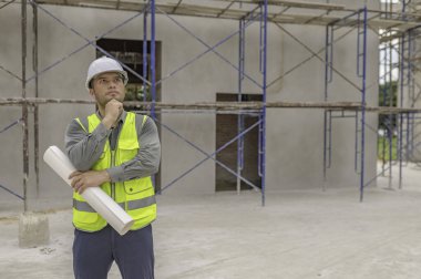 Büyük bir inşaat projesinin şantiyesinde çalışan Asyalı mühendis. İnşaat alanında fazla mesai.