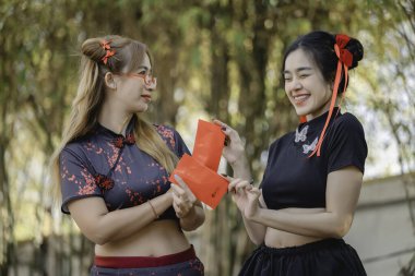 Cheongsam elbiseli güzel Asyalı kadın portresi. Elinde kırmızı gül, Tayland halkı. Mutlu Çin yeni yılı konsepti.