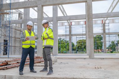 Büyük bir inşaat projesinde çalışan iki Asyalı mühendis. İnşaat alanında fazla mesai yapıyorum. Mühendis ekibi olay yerinde..