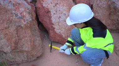 Üniformalı kadın mühendis kayaların kalitesini kontrol ediyor. Gündüz vakti dışarıda çalışan Asyalı kadın mühendis. 