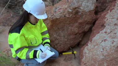Üniformalı kadın mühendis kayaların kalitesini kontrol ediyor. Gündüz vakti dışarıda çalışan Asyalı kadın mühendis. 