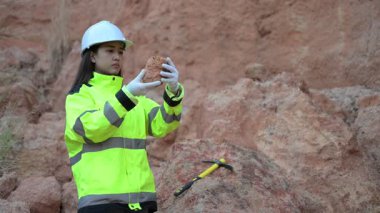 Üniformalı kadın mühendis kayaların kalitesini kontrol ediyor. Gündüz vakti dışarıda çalışan Asyalı kadın mühendis. 