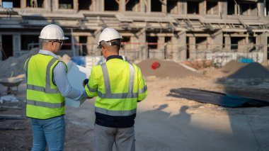 Büyük bir inşaat projesinin şantiyesinde çalışan iki Asyalı mühendis inşaat sahasında fazla mesai, inşaat alanında mühendislik diski.