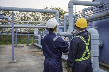 Petrol rafinerisi bölgesinde çalışan Petrokimya mühendisleri. Endüstriyel teknisyenler, fabrikadaki enerji enerji gaz sistemini denetliyor..