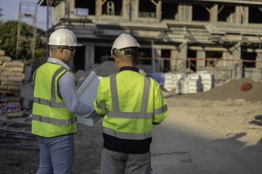 Büyük bir inşaat projesinin şantiyesinde çalışan iki Asyalı mühendis inşaat sahasında fazla mesai, inşaat alanında mühendislik diski.