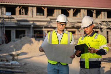 Büyük bir inşaat projesinin şantiyesinde çalışan iki Asyalı mühendis inşaat sahasında fazla mesai, inşaat alanında mühendislik diski.