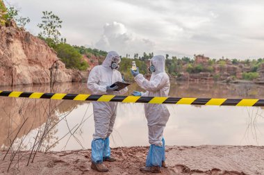 Su analizi üzerinde çalışan koruyucu üniforma giyen bilim adamları ya da biyologlar. Çevre mühendisleri tehlikeli alanlarda su kalitesini kontrol ederler.