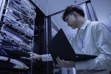 Bilgisayar mühendisi sunucu odasında ağ kuruyor, Sistem Bakım teknisyeni, erkek mühendis modern veri merkezinde sunucu odasında çalışıyor.