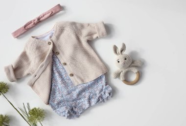 Bebek organik örülmüş kıyafetlerin üst görüntüsü. Yumuşak pastel renkler bebek kıyafetleri bembeyaz üzerine serilmişti. Küçük çocuk modası.