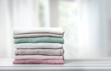 Stack of clothes on table empty copy space.House keeping. Warm knitted woolen folded clothing stacked. Laundry.