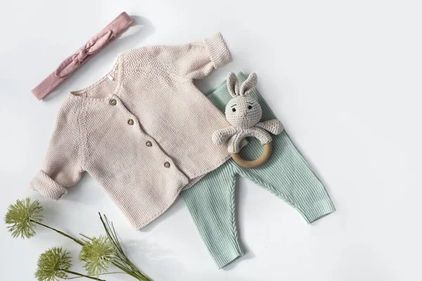 Baby organic  knitted  clothes top view. Soft pastel colors infant clothing flat lay on white. Little child fashion.