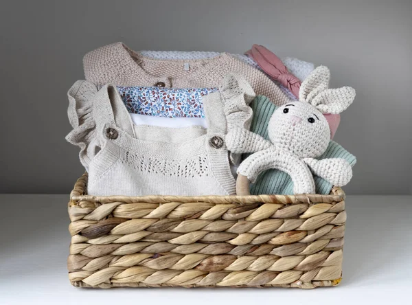 Baby stuff, organic clothes set in basket indoors.Maternity concept.Nursery,Newborn supplies. Pastel knitted infant clothing.