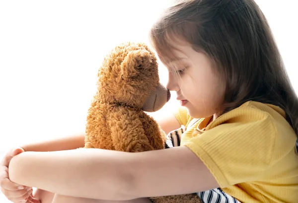 Caucasian child girl hugs teddy bear toy, Little kid portrait on white background, friendship and relationship concept. Feelings and emotions.Loneliness.