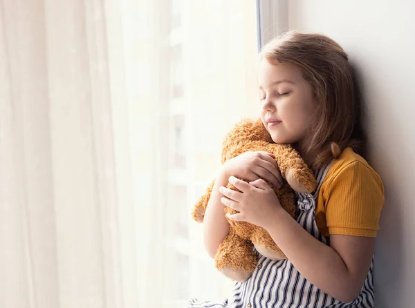 Little girl hugs plush toy empty space background. Friendship and relationship. Caucasian kid dreaming with closed eyes. Emotional scene. Toddler with teddy bear.