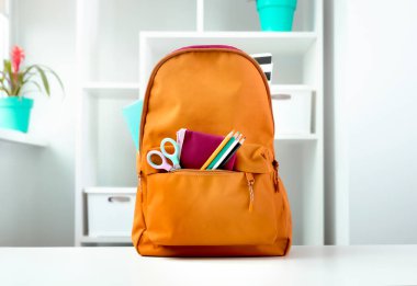 İçinde okul malzemeleri olan turuncu sırt çantası. Okula dönelim. Eğitici nesne.