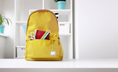 İçinde okul aksesuarları olan sarı sırt çantası. Okul malzemeleri, eşyalar. Okula boş kopya alanı beyaz arkaplan.