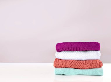 Bir yığın katlanmış giysi, boş alan arkaplanı, hiç kimse. Çamaşır, kış giysileri. Yıkanmış renkli giysiler..