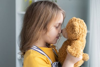 Güzel beyaz kız oyuncak ayı tutuyor, oyuncaklı çocuk, çocuk portresi içeride. Mutlu çocukluk. Aşk konsepti. İlişki. Arkadaşlık..