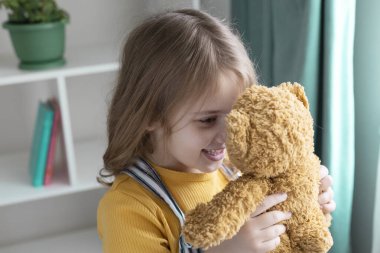 Beyaz çocuk oyuncak ayıyla oynuyor, oyuncak ile mutlu çocuk, ilişki konsepti, çocukluk. Güzel küçük bebek portresi.