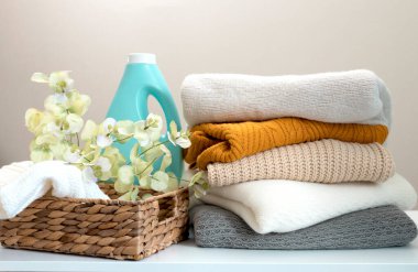 Fabric softener, washing gel, laundry.Stack of knitwear. Knitted clothes on table nobody.Fresh laundry. clipart