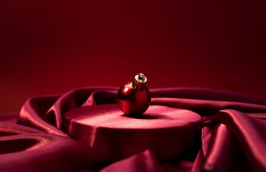 Platformdaki boş alan arka planında kırmızı Noel takısı, Xmas tatil ürünleri sergisi, ışıklandırılmış lüks zarif sahne. Parlak reklam arkaplanı. Yeni yıl kartı, koyu renkli reklam afişi..