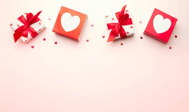 Sevgililer Günü arkaplanı, kırmızı fiyonklu hediye kutusu, kalplerin üst tarafı boş fotokopi alanı ile süslenmiş. Romantik tatil dekorasyonu nesneleri.