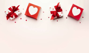 Sevgililer Günü arkaplanı, kırmızı fiyonklu hediye kutusu, kalplerin üst tarafı boş fotokopi alanı ile süslenmiş. Romantik tatil dekorasyonu nesneleri.