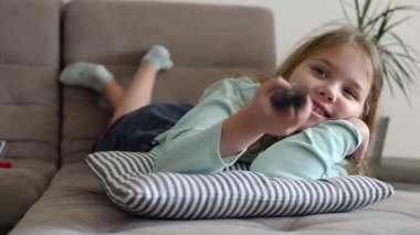 Kafkasyalı çocuk kanepede uzanıp televizyon izliyor, pilot ve uzaktan kumandayı kullanıyor. İçeride mutlu bir çocuğun eğlenceli bir konsepti var..