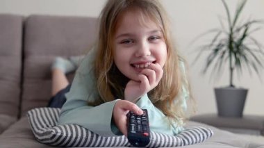 Kafkasyalı çocuk kanepede uzanıp televizyon izliyor, pilot ve uzaktan kumandayı kullanıyor. İçeride mutlu bir çocuğun eğlenceli bir konsepti var..