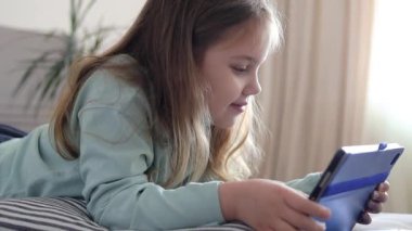 Kafkasyalı çocuk tablet kullanıyor, oyun hamuru. İnternet eğlencesi. Aleti olan çocuk.