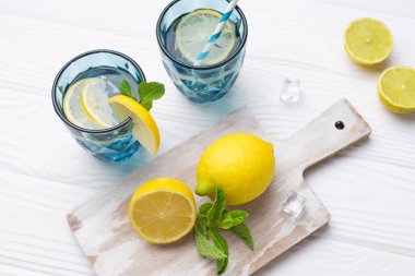 Limon ve limonla süslenmiş beyaz ahşap masada bir bardak limon suyu. Taze narenciye suyu. Ev yapımı ferahlatıcı içecek. Daha iyi bir içecek..