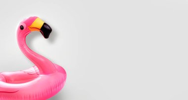 Boş gri arka planda pembe plastik plaj flamingosu yüzer. Deniz seyahati konsepti. Plaj gezisi. Deniz tatil beldesi..