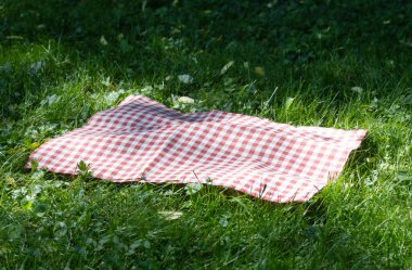 Kırmızı piknik masa örtüsü, kumaş, yeşil çimen boş alanda kareli havlu. Yemek reklam şablonu. Yaz dönemi ülke tasarımı..