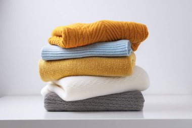 Sonbahar örgüsü, katlanmış kumaş yığını. Masaya örgü yığını. Sonbahar tarzı çamaşır, yün kazak yığını..