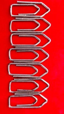 Gümüş renkli ataçlar kırmızı arka planda sıkıca dizilmişler.