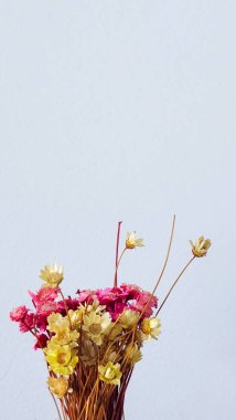 Beyaz arkaplanda pembe ve sarı yapay çiçekler