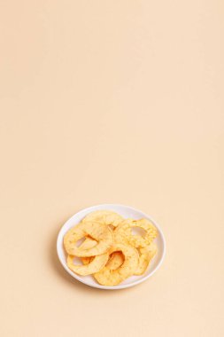 Açık bej arka planda beyaz seramik tabakta elma parçacıkları olan minimalist kompozisyon. Sağlıklı tatlı atıştırmalık.