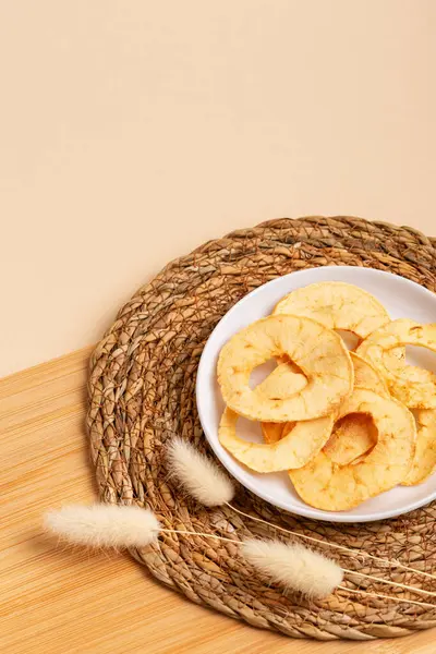 stock image Apple chips on a white ceramic round plate on a wooden desk on a beige background in rustic style.