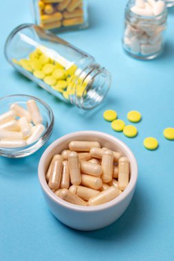 Yukarıdan mavi zemin üzerinde beslenme takviyeleri, vitaminler ve mineral tabletleri.