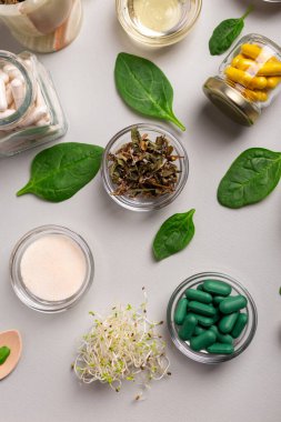 Homeopatik ilaçlar, kapsüller, yeşil yapraklar ve yukarıdan gelen bitkiler. Homeopatik tıp üst görüşü. Homeopati ve alternatif tıp.