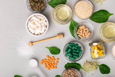 Birçok homeopatik ilaç, hap, tablet, şifalı bitkiler, yeşil yapraklar ve diğer doğal organik ürünler açık gri arka planda, üst manzarada güzel bir kompozisyonda. Homeopati ve alternatif tıp.