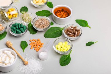 Homeopatik ilaçlar, haplar, tabletler, yeşil yapraklar ve diğer doğal organik ürünler açık gri arka planda güzel bir kompozisyonda. Homeopati ve alternatif tıp.