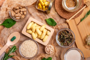 Homeopati ve alternatif tıp. İlaçlar, haplar, kapsüller, ahşap bir masanın üstündeki küçük kaselerde kırsal tarzda takviyeler. Üst düzey homeopatik ilaçlar, düz uzanmış yaşam.