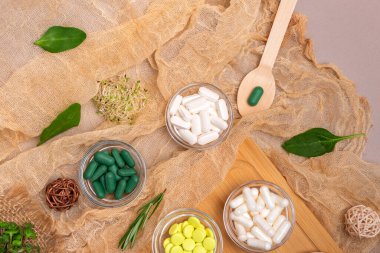 Homeopati ve alternatif tıp. İlaçlar, haplar, kapsüller, ahşap bir masanın üstündeki küçük kaselerde kırsal tarzda takviyeler. Üst düzey homeopatik ilaçlar, düz uzanmış yaşam.