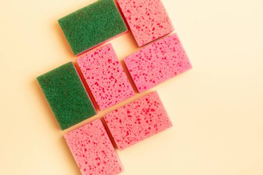 Bej arka planda bulaşık yıkamak için pembe mutfak süngeri, üst manzara. Ev ödevi. Ev işleri işte. Bulaşık yıkama.